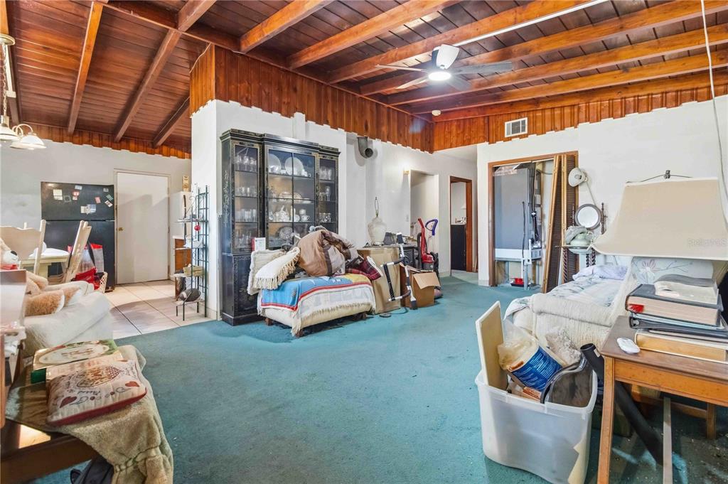 A living room features a wood-paneled vaulted ceiling, green carpeting, and a dark china cabinet — 214 BLAKE AVENUE, COCOA, FL