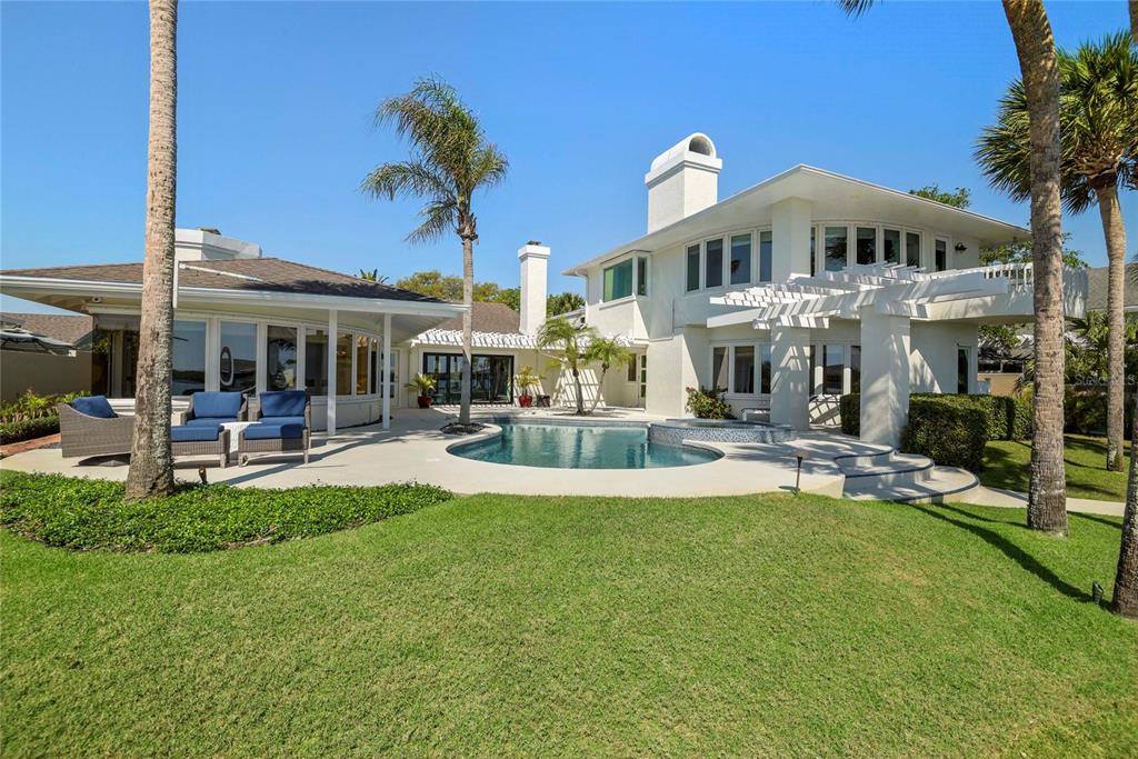 A white two-story house features a backyard swimming pool, patio furniture, and palm trees — 1215 COMMODORE DRIVE, NEW SMYRNA BEACH, FL