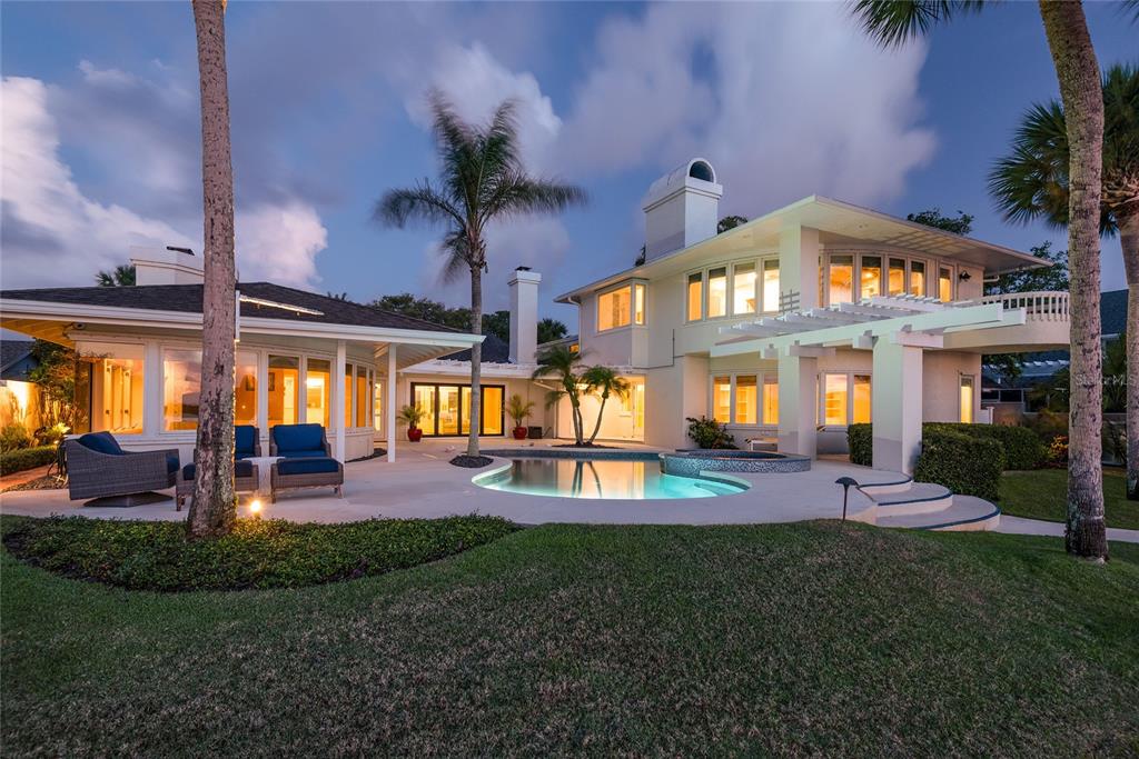 A two-story house with a pool, patio, and palm trees at twilight — 1215 COMMODORE DRIVE, NEW SMYRNA BEACH, FL