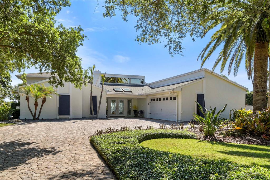 A single-story house with a paved driveway, white exterior, and a two-car garage — 1215 COMMODORE DRIVE, NEW SMYRNA BEACH, FL