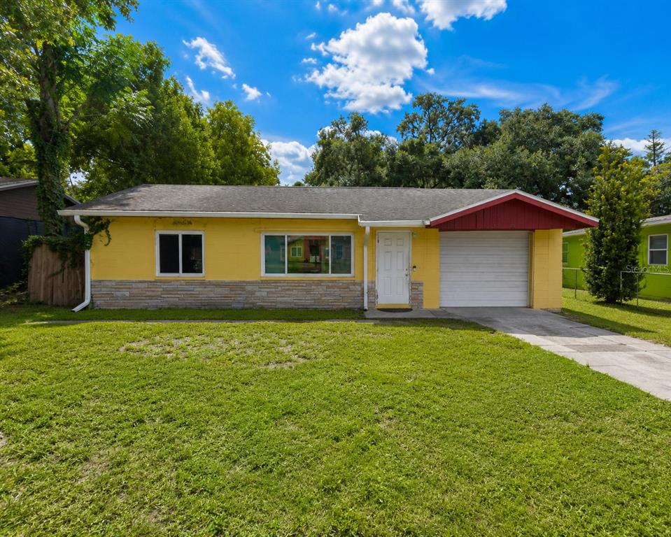 A single-story yellow house with a stone base, a white garage door, and a red awning — 1740 S RIO GRANDE AVENUE, ORLANDO, FL
