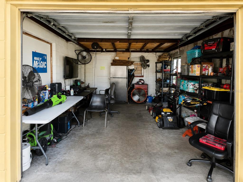 A cluttered garage features a concrete floor, storage shelving, a refrigerator, and various tools — 1740 S RIO GRANDE AVENUE, ORLANDO, FL