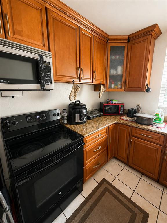 A kitchen features wood cabinets, granite countertops, a black stove, and a stainless steel microwave — 1740 S RIO GRANDE AVENUE, ORLANDO, FL