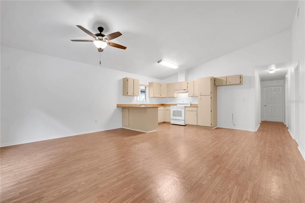An open-concept kitchen and living area features light wood-look flooring and beige cabinetry — 623 PARQUE DRIVE, ORMOND BEACH, FL