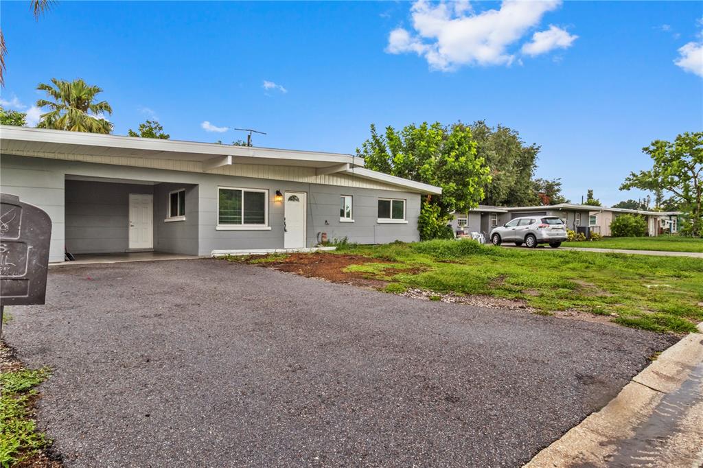 A single-story gray house with a carport and an asphalt driveway under a blue sky — 5711 21ST STREET W, BRADENTON, FL