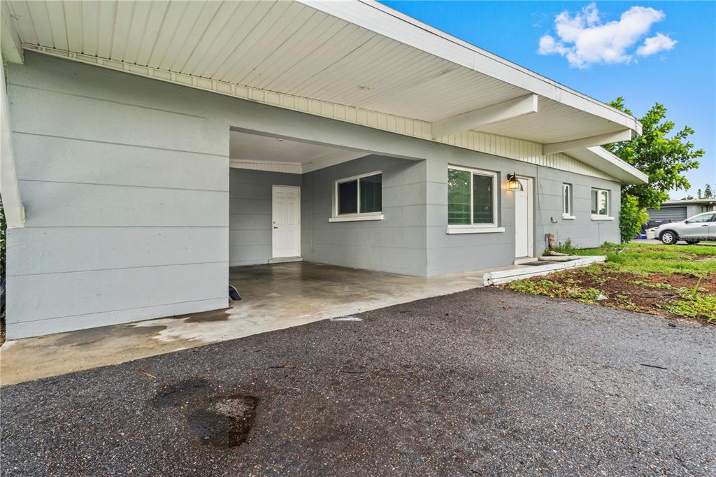 A gray house exterior features a covered carport, a white front door, and several windows — 5711 21ST STREET W, BRADENTON, FL
