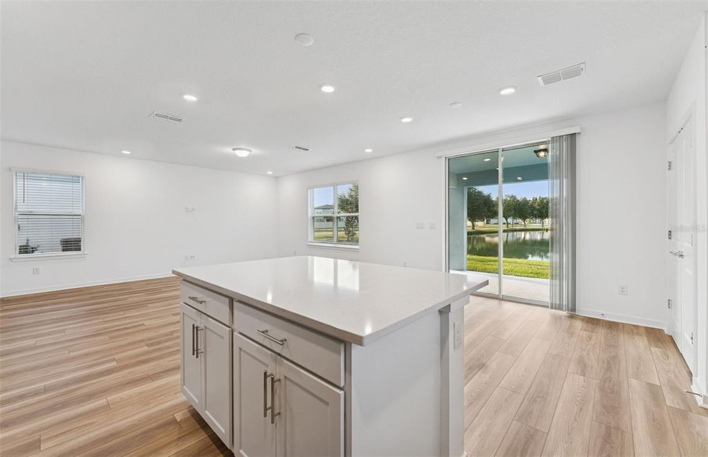 A kitchen island with light gray cabinets and white countertops sits in an open living space — 9748 CRESCENT MOON DRIVE, RIVERVIEW, FL