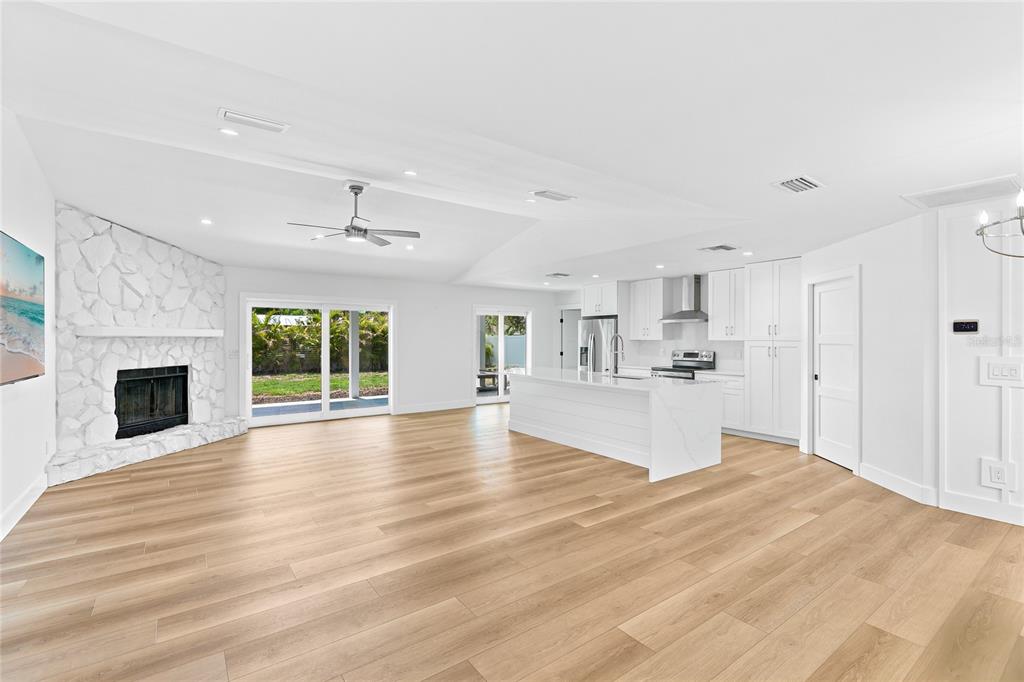 A modern white kitchen features a large island, stainless steel appliances, and light wood flooring — 206 73RD STREET NW, BRADENTON, FL