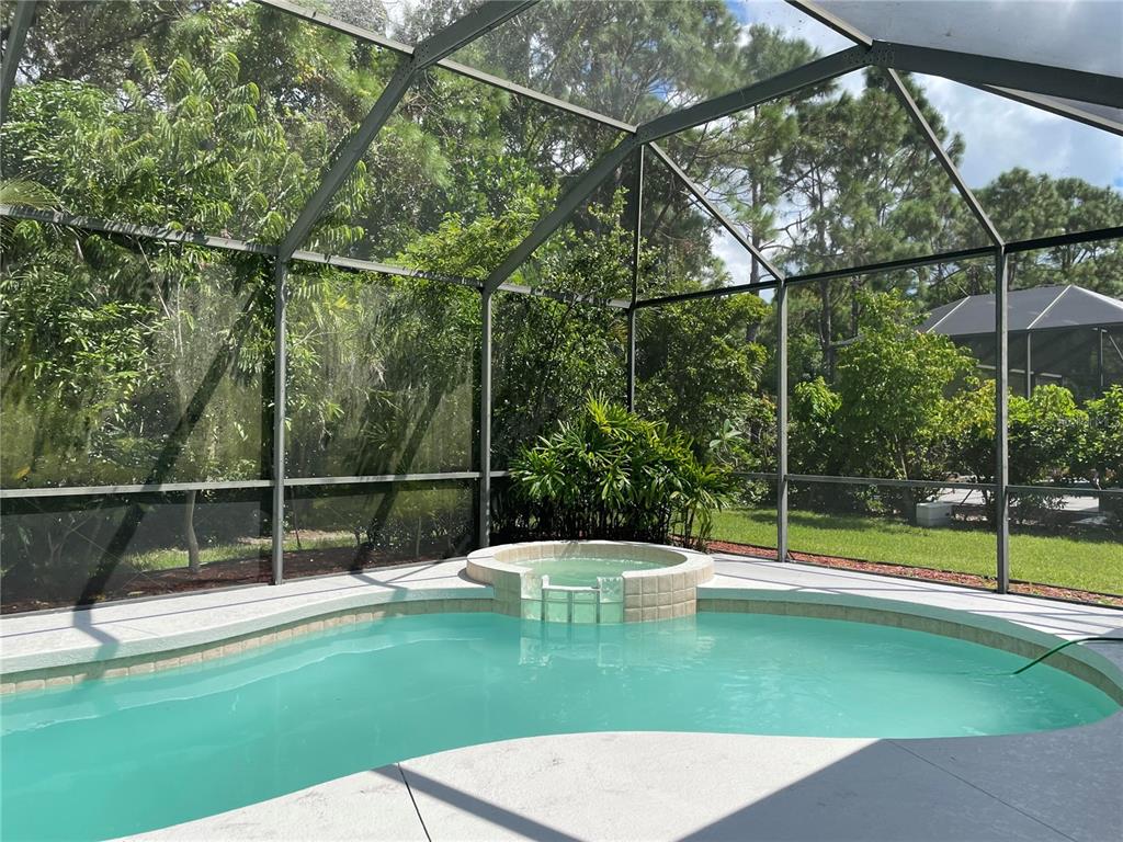 A screened-in swimming pool and attached spa are surrounded by lush green trees — 759 FORDINGBRIDGE WAY, OSPREY, FL