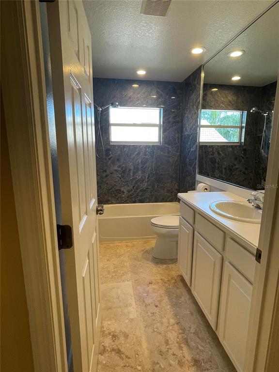 A bathroom features a white vanity, a toilet, and a bathtub with dark marble walls — 759 FORDINGBRIDGE WAY, OSPREY, FL