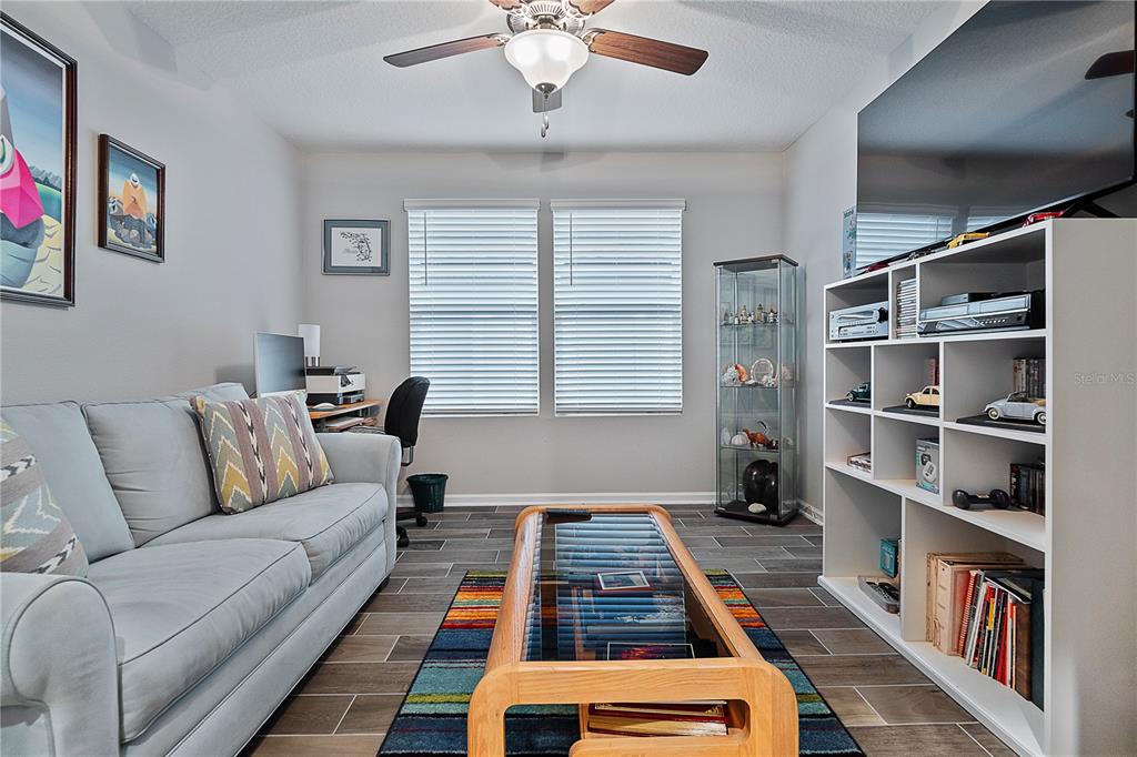 A living room featuring a gray sofa, a glass-topped coffee table, and a white bookshelf — 285 OSPREY LANDING LANE, ST AUGUSTINE, FL