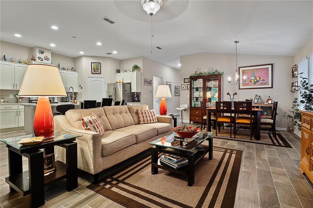 An open-concept living and dining area features a beige sofa, glass coffee table, and tile flooring — 285 OSPREY LANDING LANE, ST AUGUSTINE, FL