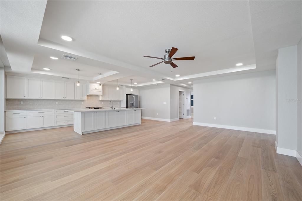 A spacious kitchen with white cabinetry and a large island opens into a living area — 14048 GULF BOULEVARD UNIT 402, MADEIRA BEACH, FL