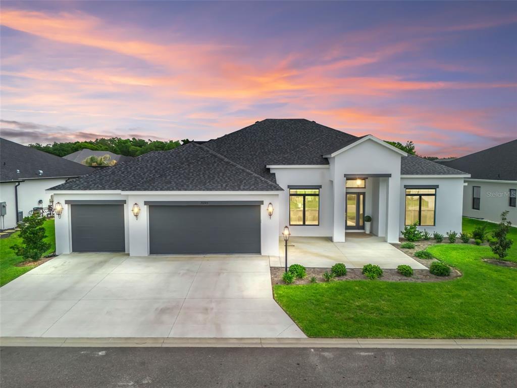 A screened-in swimming pool with a sun shelf and water feature at sunset — 7095 JENNINGS COURT, THE VILLAGES, FL