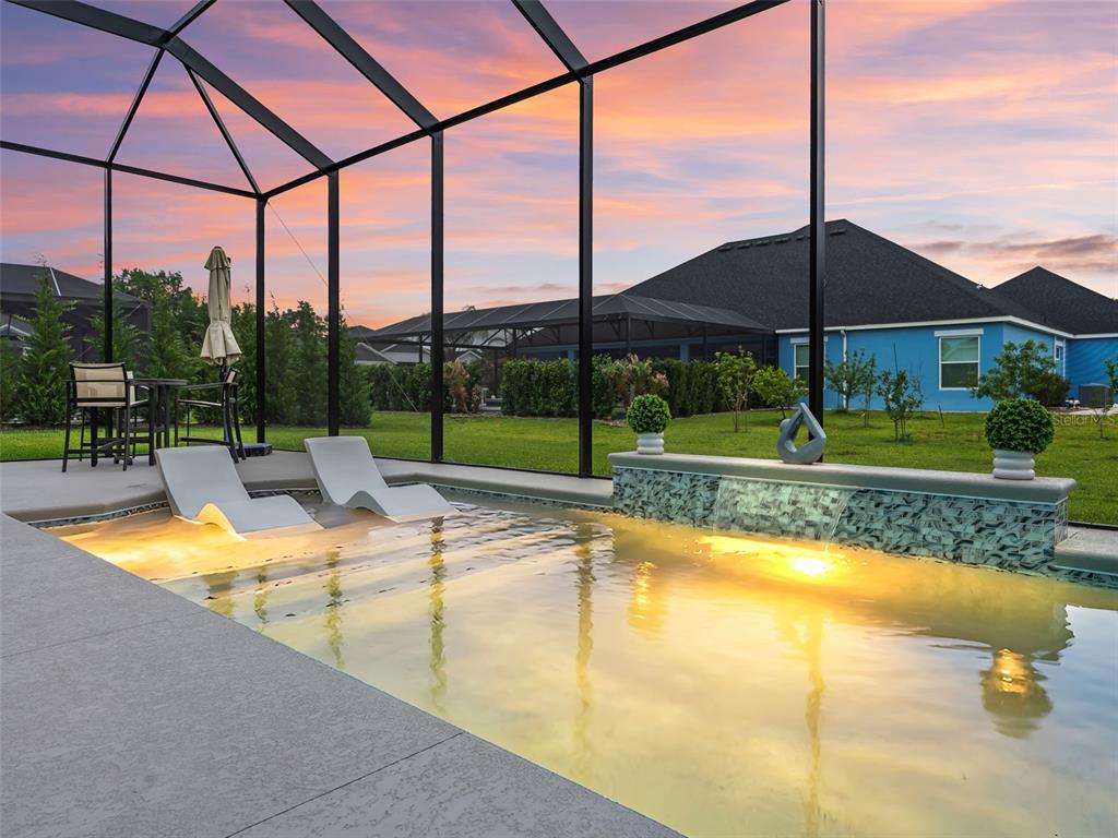 A screened-in patio features a swimming pool with a sun shelf and a water feature — 7095 JENNINGS COURT, THE VILLAGES, FL