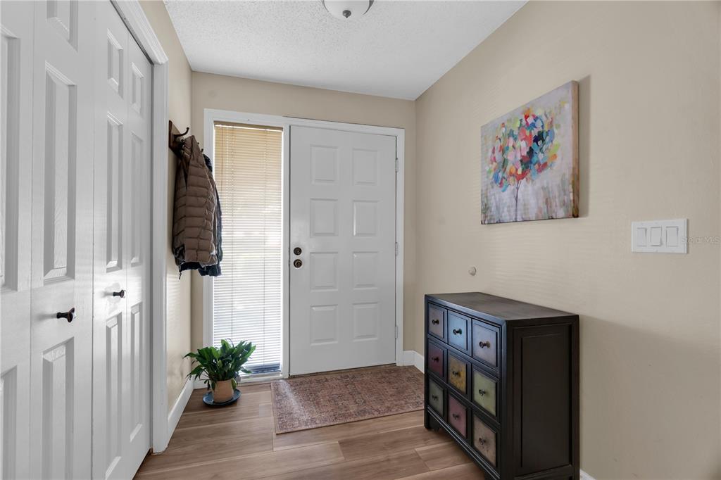 An entryway features a white front door, a dark wooden dresser, and light wood flooring — 2866 COUNTRYBROOK DRIVE UNIT 12, PALM HARBOR, FL