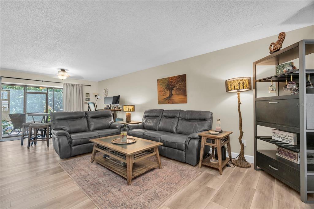 A living room features two grey leather sofas, a wooden coffee table, and wood-look flooring — 2866 COUNTRYBROOK DRIVE UNIT 12, PALM HARBOR, FL