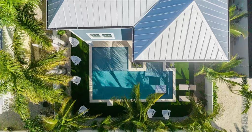 An aerial view shows a house with a metal roof, a swimming pool, and palm trees — 2210 AVENUE A, BRADENTON BEACH, FL