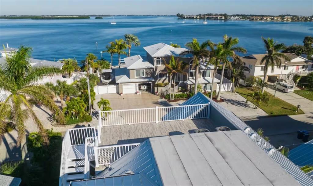 An elevated view of a waterfront house with a rooftop deck and metal roof — 2210 AVENUE A, BRADENTON BEACH, FL