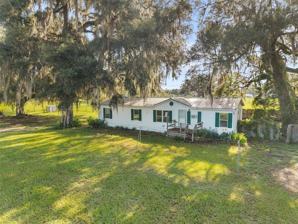 A white single-wide mobile home sits on a grassy lot under large oak trees — 360 & 390 SE 30TH AVENUE, TRENTON, FL