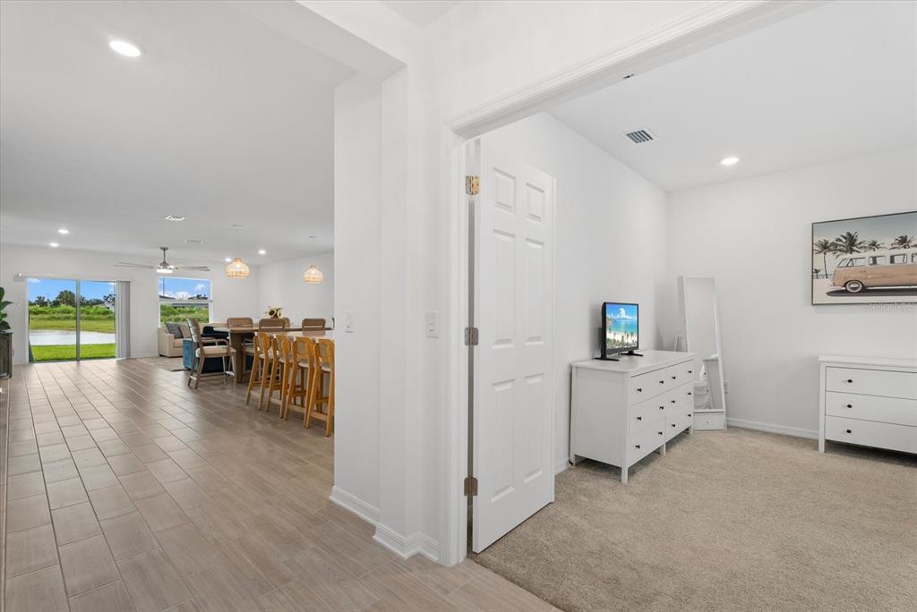 A view from a carpeted bedroom looking into an open-concept kitchen and living area — 10032 LAST LIGHT GLEN, PARRISH, FL