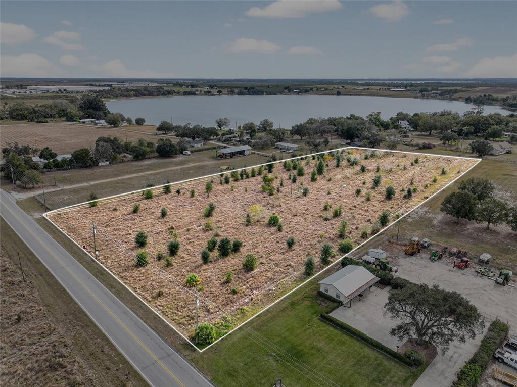 An aerial view shows a vacant, rectangular lot bordered by a road and a lake — FORT MEADE ROAD N, FROSTPROOF, FL