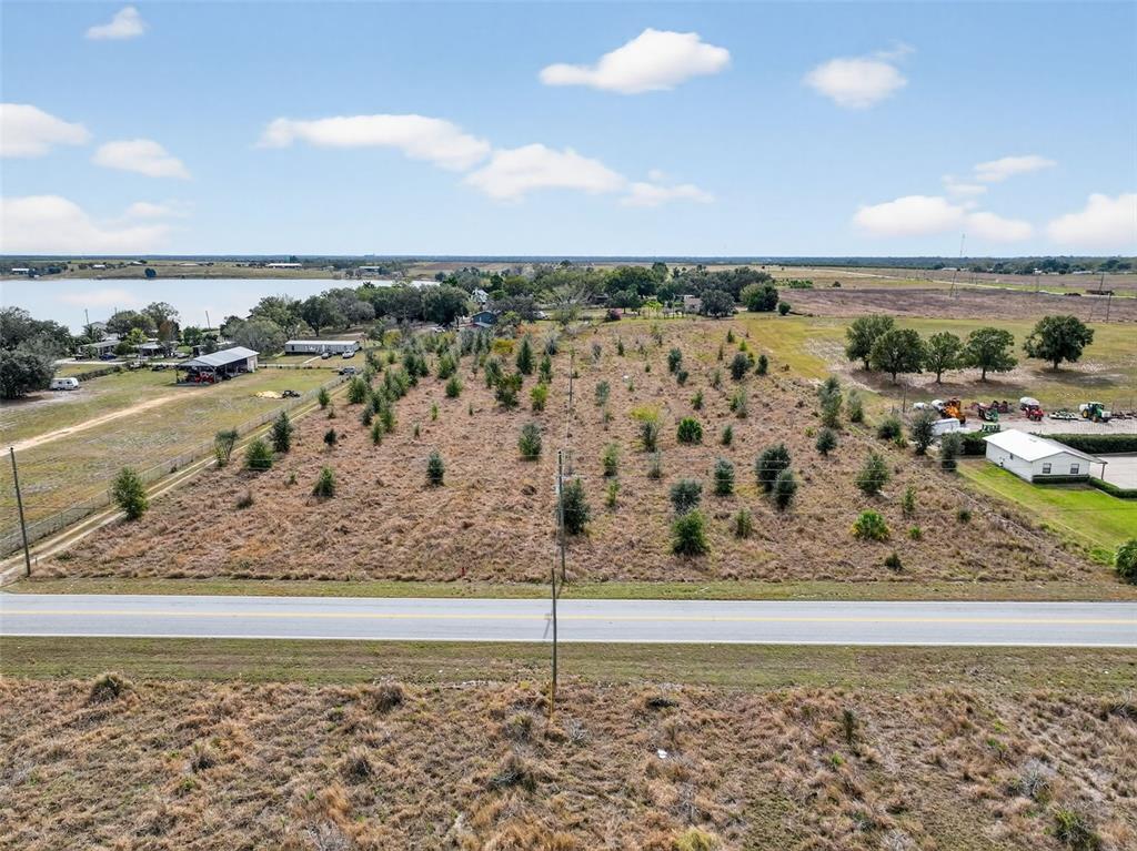An aerial view shows a vacant, grassy lot with scattered small trees bordering a road — FORT MEADE ROAD N, FROSTPROOF, FL