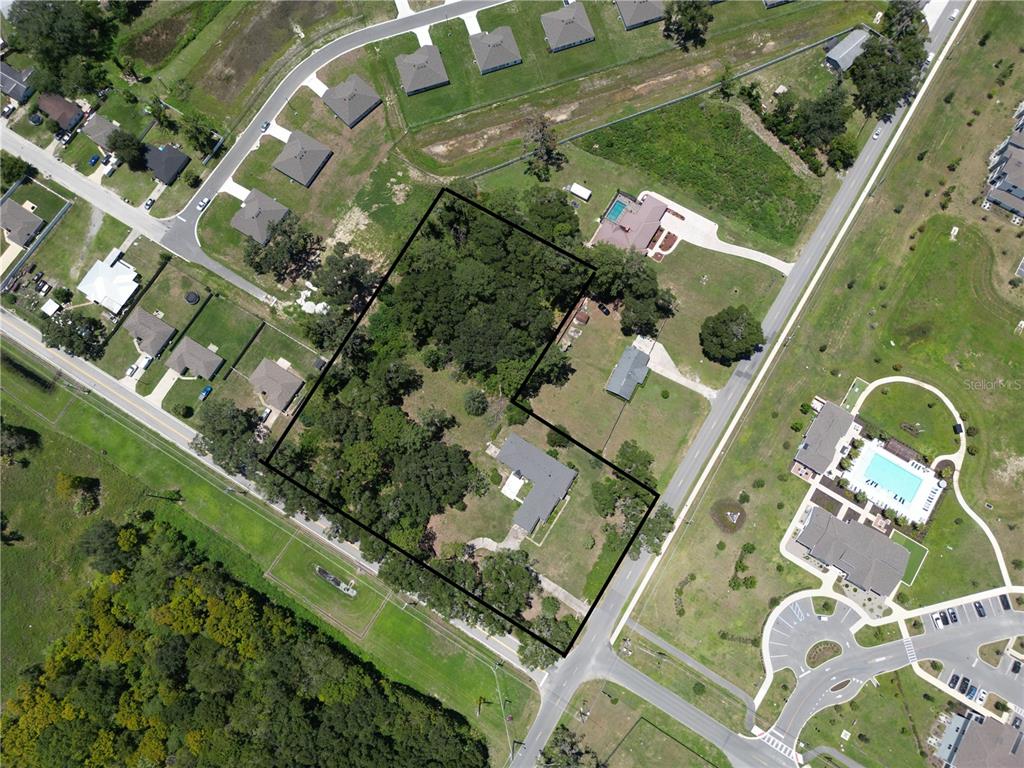 An aerial view shows a residential lot outlined in black, featuring trees and two houses — 2100 NW 21ST STREET, OCALA, FL