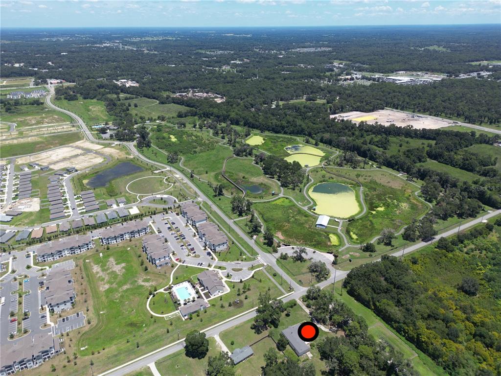 An aerial view shows a residential neighborhood, a park with ponds, and a marked house — 2100 NW 21ST STREET, OCALA, FL