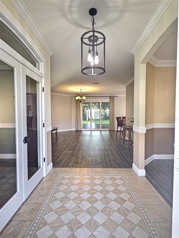 A covered front porch features a white door with sidelights, two columns, and potted plants — 55 BROOKLYN LANE, PALM COAST, FL