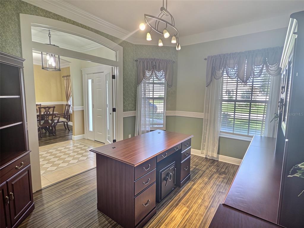 A home office with dark wood furniture is visible through open glass-paneled double doors — 55 BROOKLYN LANE, PALM COAST, FL
