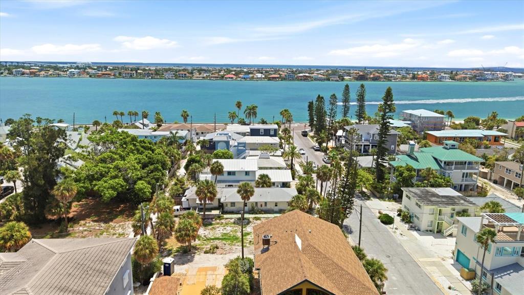 An aerial view shows a coastal neighborhood with houses, palm trees, and a large bay — 113 3RD AVENUE, ST PETE BEACH, FL
