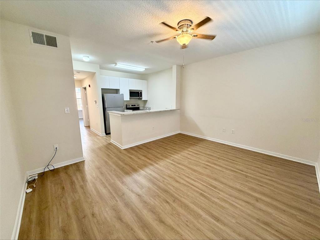 An open-concept living room features light wood-look flooring and a kitchen with a breakfast bar — 606 MARKET STREET UNIT 230, CELEBRATION, FL