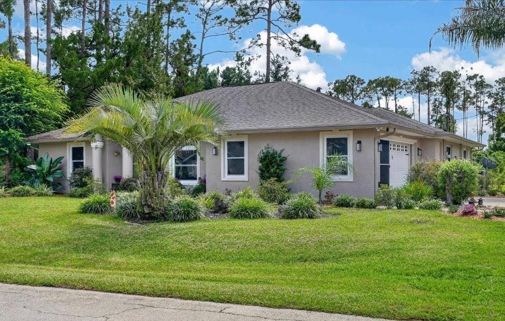 A concrete front porch features a white door, a large pillar, and potted flowers — 84 ETHAN ALLEN DRIVE, PALM COAST, FL
