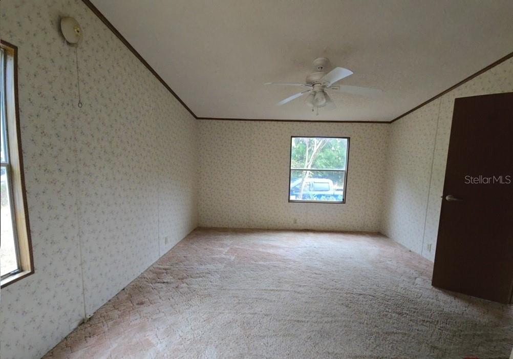 An empty bedroom features floral wallpaper, beige carpeting, a ceiling fan, and a single window — 12906 NW 38TH AVENUE, REDDICK, FL