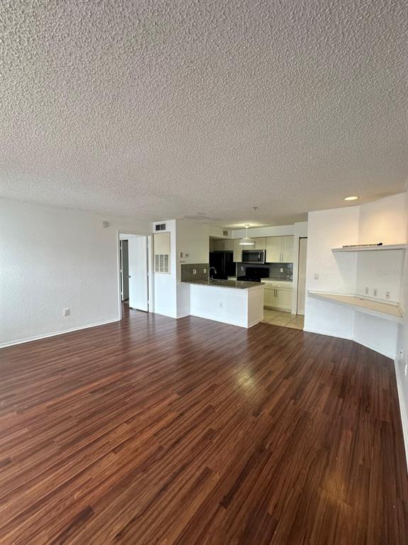 An open-concept living area with wood-look flooring, a kitchen island, and a built-in desk — 2210 GRAND CAYMAN COURT UNIT 1721, KISSIMMEE, FL