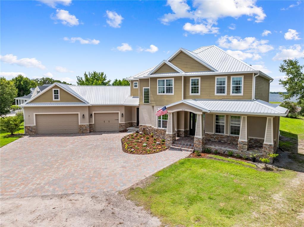 A two-story house with a metal roof, stone accents, and a paved driveway — 4664 HICKORY TREE LN, ST CLOUD, FL