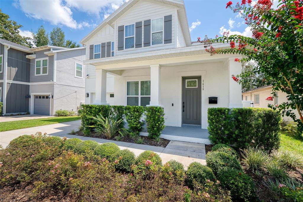A white two-story house features a covered front porch, dark gray shutters, and landscaped bushes — 1619 S OSCEOLA AVENUE, ORLANDO, FL