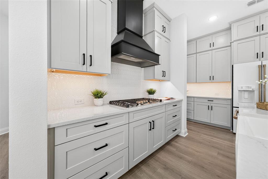 A modern kitchen features light gray cabinets, white countertops, a black range hood, and wood flooring — 1619 S OSCEOLA AVENUE, ORLANDO, FL