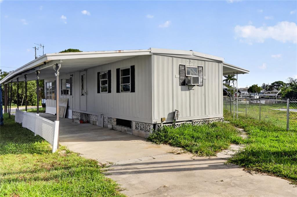 A light-colored mobile home with a carport and a window air conditioning unit — 6639 TOWER DRIVE, HUDSON, FL