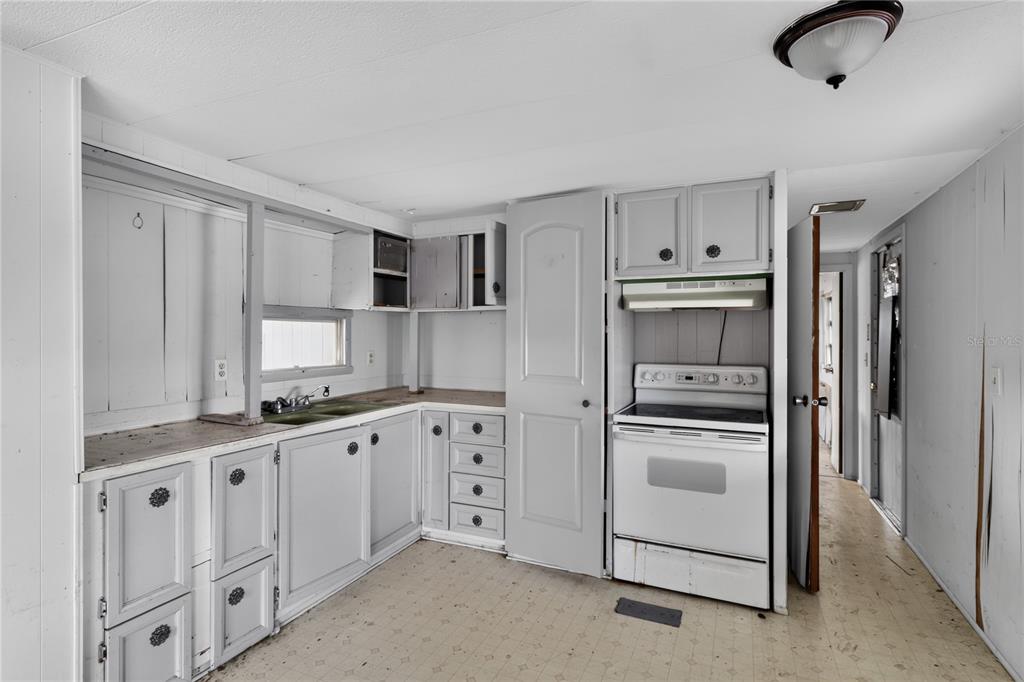 A kitchen features white cabinets, a white stove, and a window above the sink — 6639 TOWER DRIVE, HUDSON, FL