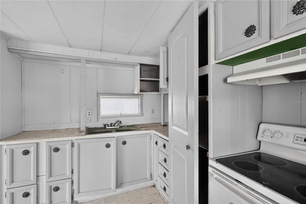 A kitchen features white painted cabinets, a sink, and an electric stove — 6639 TOWER DRIVE, HUDSON, FL