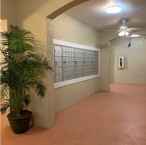 A covered outdoor mailroom features a wall of metal mailboxes, a ceiling fan, and a plant — 1216 S MISSOURI AVENUE UNIT 214, CLEARWATER, FL