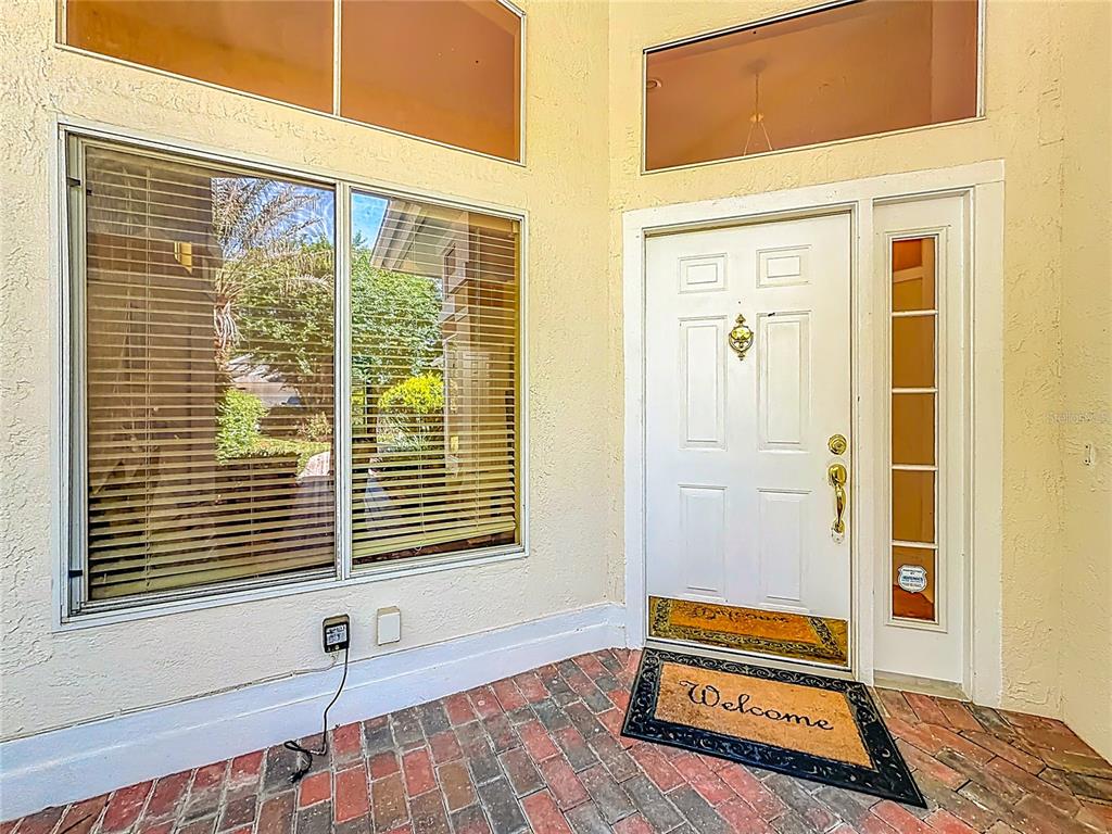 A brick-paved entryway features a white front door with a sidelight and a large window — 848 CREPE MYRTLE CIRCLE, APOPKA, FL