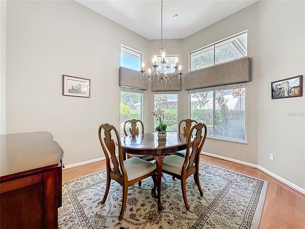 A dining area features a wooden table, four chairs, a chandelier, and large windows — 848 CREPE MYRTLE CIRCLE, APOPKA, FL