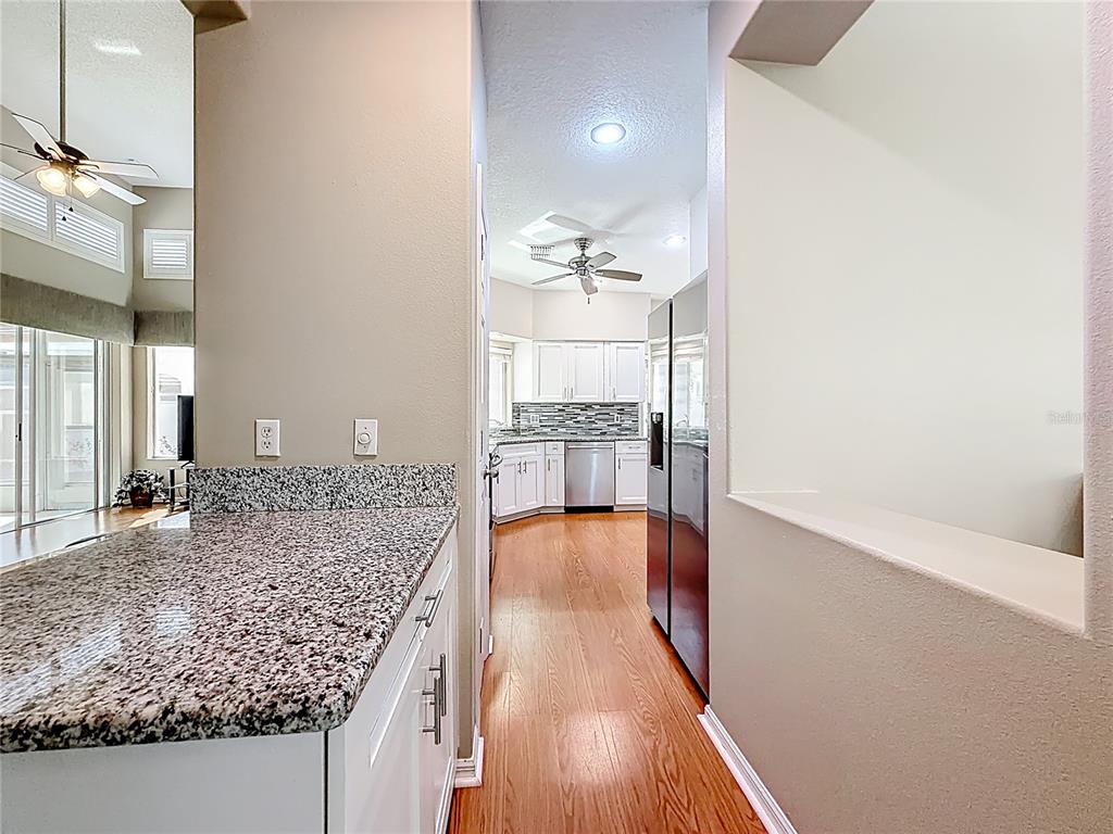 A kitchen with granite countertops and white cabinets viewed from an adjacent hallway — 848 CREPE MYRTLE CIRCLE, APOPKA, FL