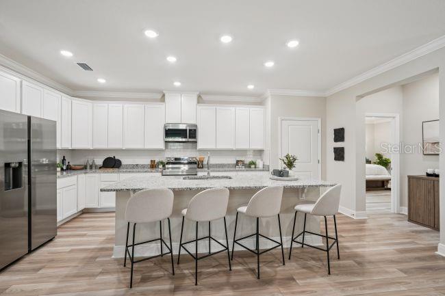 A modern kitchen features white cabinetry, stainless steel appliances, and a central island with seating — 804 SW 80TH WAY, GAINESVILLE, FL