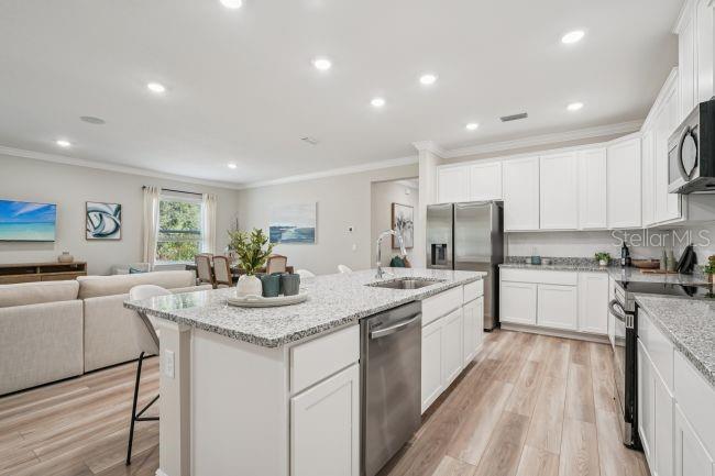 A kitchen with white cabinets, granite countertops, and stainless steel appliances opens to a living area — 804 SW 80TH WAY, GAINESVILLE, FL