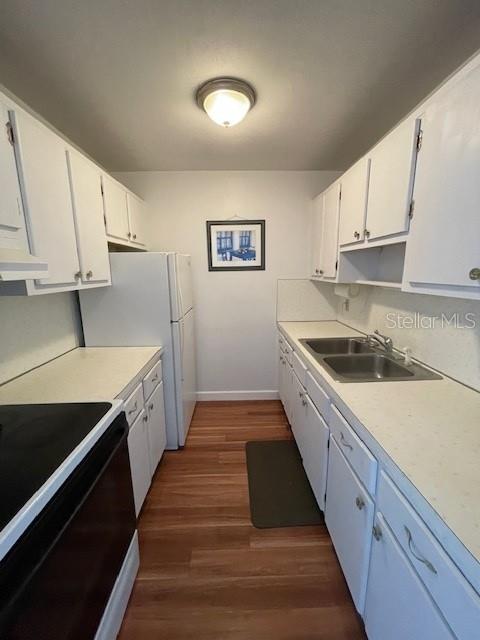 A galley kitchen features white cabinets, light countertops, a refrigerator, and wood-look flooring — 8075 112TH STREET UNIT 203, SEMINOLE, FL