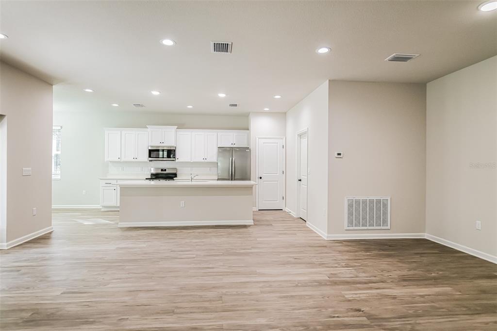 A kitchen features white cabinetry, stainless steel appliances, and a central island on wood flooring — 4744 S RAINBOW DRIVE, INVERNESS, FL